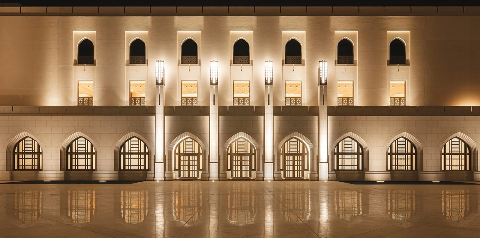 House of Musical Arts, Muscat, lit facade at night reflected in wet paving